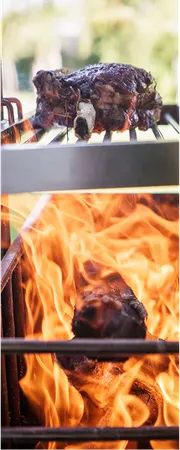 Nahaufnahme von Fleisch, das auf einem Grillrost über offenem Feuer gart.