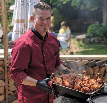 Tommy beim Grillen, der freundlich in die Kamera zwinkert.